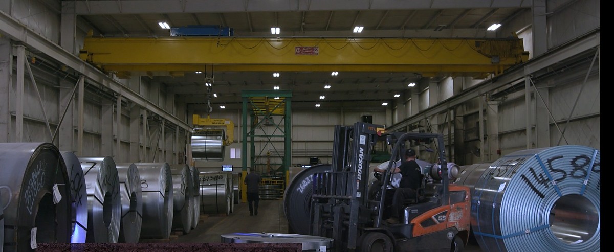 Master coils being moved with an overhead crane and forklift in coil storage